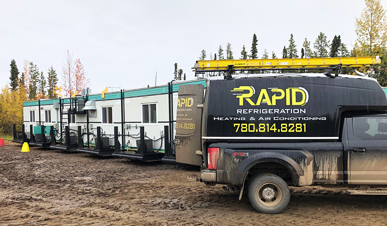 Rapid Refrigeration service truck parked next to trailers on oilfield camp